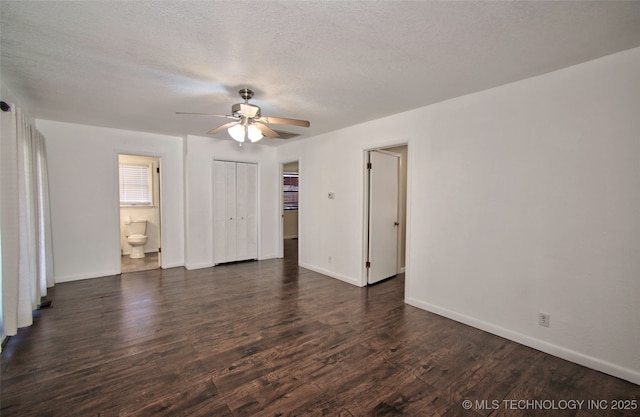 empty room with a textured ceiling, ceiling fan, and dark hardwood / wood-style flooring