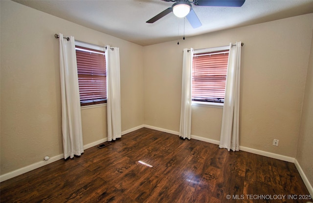 empty room with ceiling fan and dark hardwood / wood-style flooring