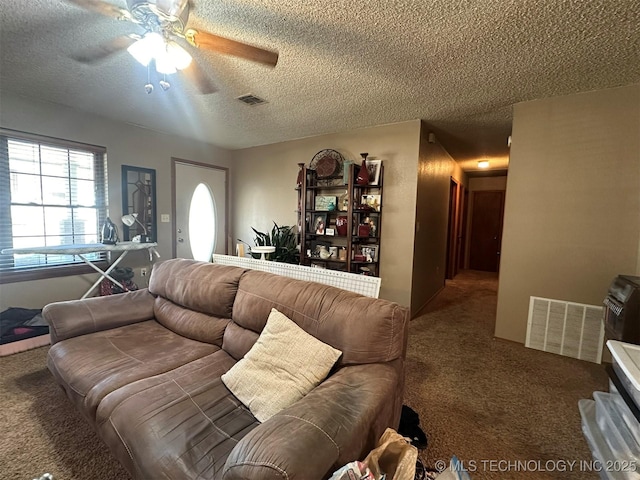 living room with a textured ceiling, ceiling fan, and carpet floors