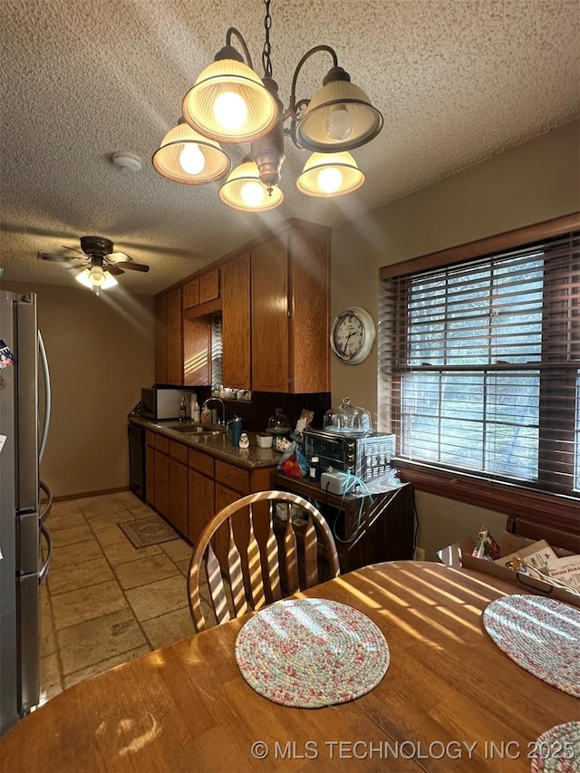 kitchen with dishwasher, ceiling fan, sink, a textured ceiling, and stainless steel refrigerator