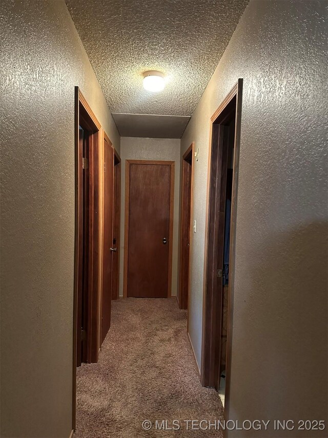 corridor with carpet and a textured ceiling