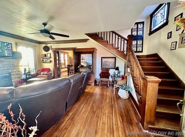 living room with crown molding, ceiling fan, a fireplace, and hardwood / wood-style flooring