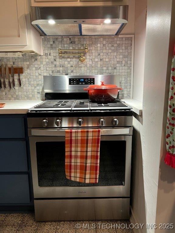 kitchen with light tile patterned floors, white cabinetry, range hood, stainless steel range with gas stovetop, and decorative backsplash