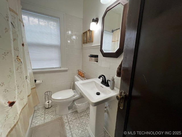 bathroom with toilet, tile patterned flooring, and tile walls