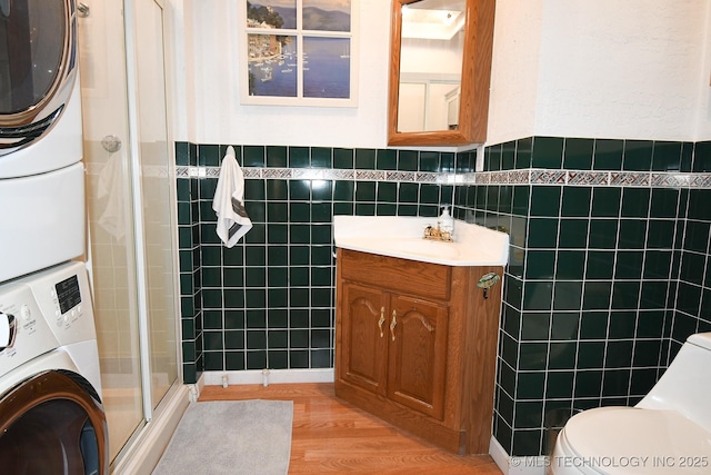 bathroom with vanity, tile walls, toilet, and stacked washing maching and dryer