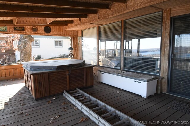 wooden deck with a hot tub and a water view