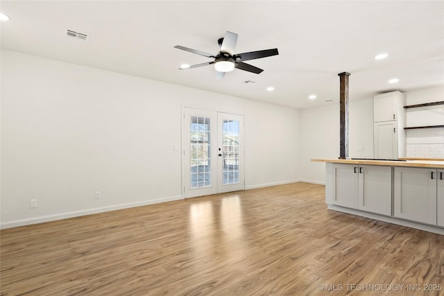 unfurnished living room featuring light hardwood / wood-style floors, ceiling fan, and french doors