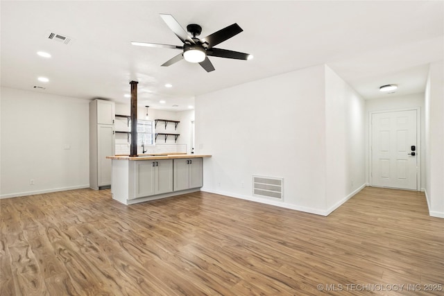 unfurnished living room featuring sink, light hardwood / wood-style flooring, and ceiling fan