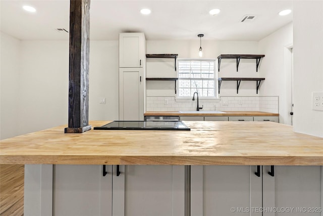 kitchen with white cabinets, a kitchen bar, decorative backsplash, sink, and light hardwood / wood-style flooring