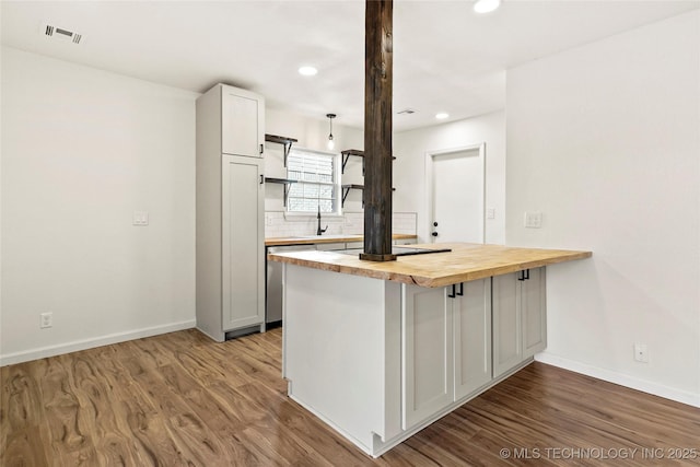 kitchen with kitchen peninsula, dishwasher, white cabinetry, light hardwood / wood-style floors, and butcher block counters