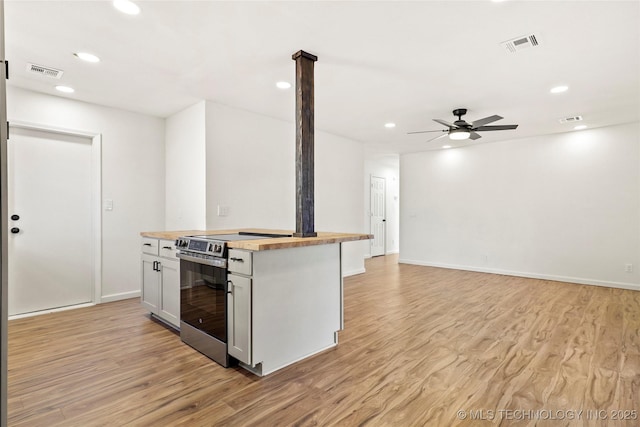 kitchen featuring light hardwood / wood-style floors, butcher block countertops, stainless steel electric range oven, and ceiling fan