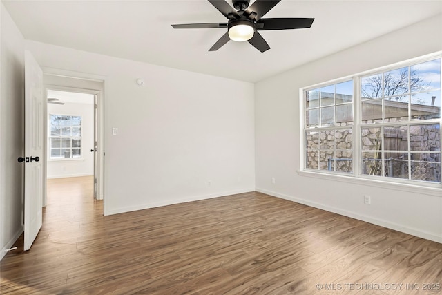 empty room with ceiling fan, plenty of natural light, and hardwood / wood-style floors