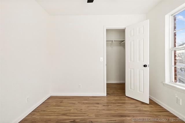 unfurnished bedroom with a closet, hardwood / wood-style flooring, and multiple windows