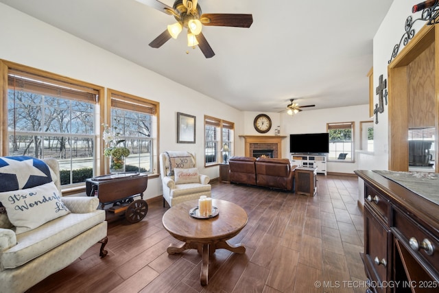 living room featuring ceiling fan, dark wood-type flooring, and a brick fireplace