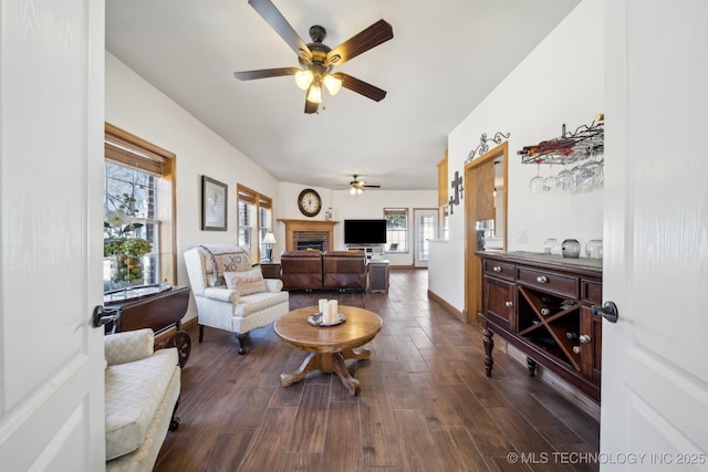 living room with ceiling fan, a brick fireplace, and dark hardwood / wood-style flooring