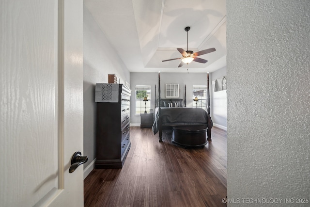 bedroom featuring ceiling fan, dark hardwood / wood-style floors, and a tray ceiling