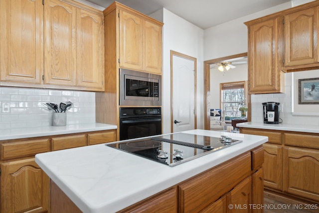 kitchen with decorative backsplash, black appliances, ceiling fan, and a kitchen island