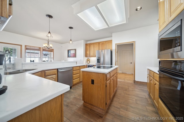 kitchen with kitchen peninsula, hanging light fixtures, a kitchen island, a chandelier, and stainless steel appliances