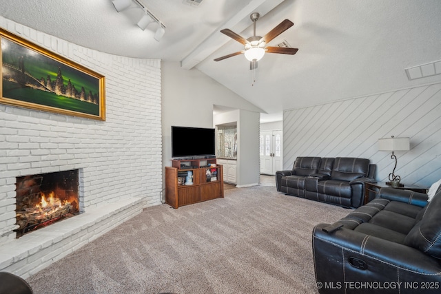 living room with wooden walls, vaulted ceiling with beams, carpet flooring, a brick fireplace, and a textured ceiling