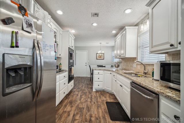 kitchen with pendant lighting, sink, dark wood-type flooring, white cabinetry, and stainless steel appliances