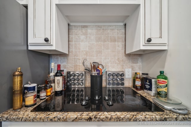 kitchen with black electric cooktop, decorative backsplash, dark stone counters, and white cabinets