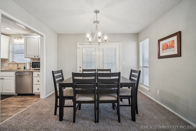 carpeted dining space featuring an inviting chandelier, sink, and a textured ceiling