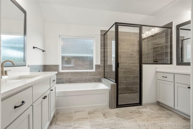 bathroom featuring independent shower and bath, vanity, and a healthy amount of sunlight