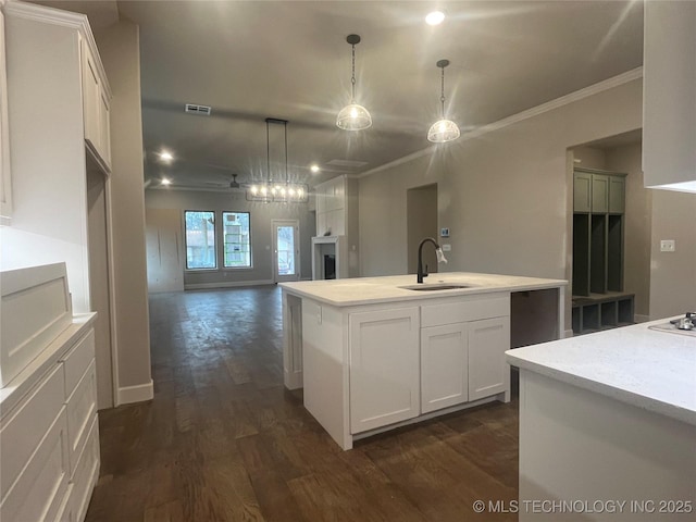 kitchen featuring sink, dark wood-type flooring, a kitchen island with sink, white cabinetry, and decorative light fixtures