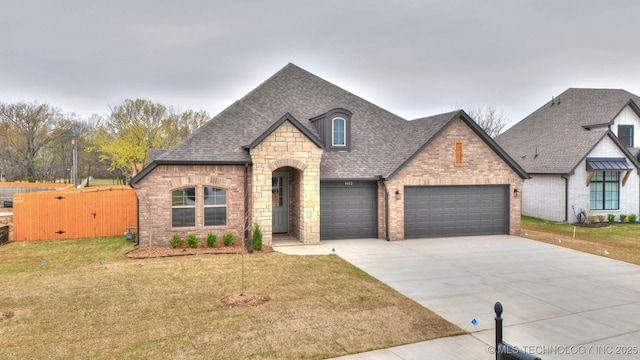french provincial home featuring roof with shingles, a front lawn, stone siding, concrete driveway, and a garage