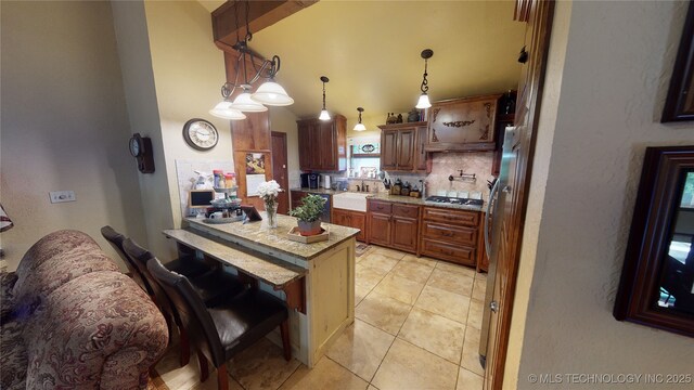 kitchen featuring pendant lighting, a breakfast bar, tasteful backsplash, stainless steel gas cooktop, and light tile patterned flooring