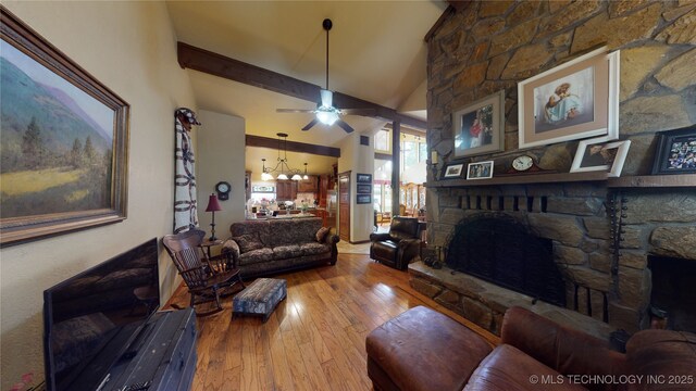 living room with high vaulted ceiling, light wood-type flooring, beamed ceiling, a fireplace, and ceiling fan with notable chandelier