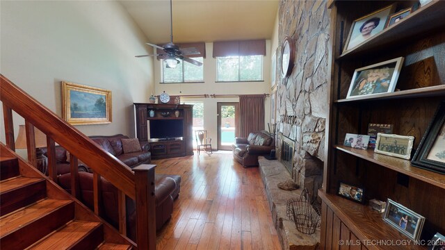 living room with hardwood / wood-style floors, ceiling fan, and a high ceiling