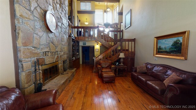 living room with hardwood / wood-style flooring, a high ceiling, and a fireplace