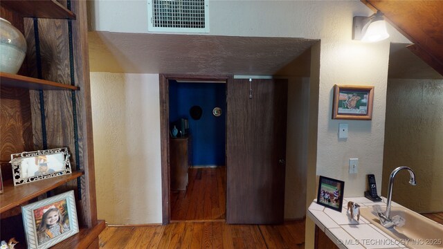 hallway featuring wood-type flooring and sink