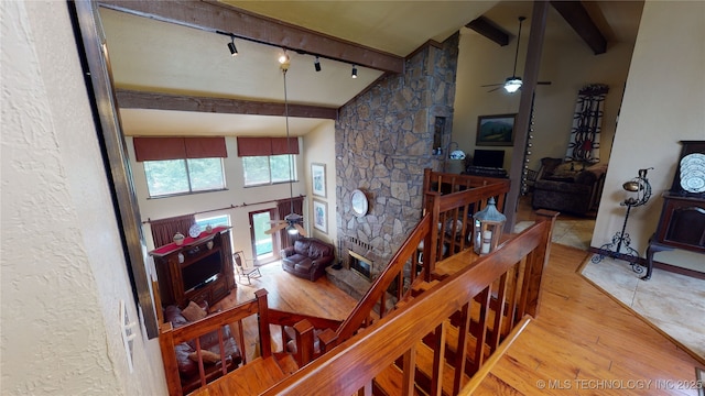 staircase featuring hardwood / wood-style flooring, track lighting, ceiling fan, and lofted ceiling with beams