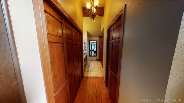 hallway featuring a notable chandelier and light hardwood / wood-style flooring