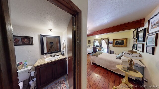 bedroom featuring sink, hardwood / wood-style floors, and a textured ceiling