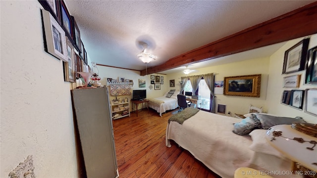 bedroom with ceiling fan, beamed ceiling, dark hardwood / wood-style floors, and a textured ceiling