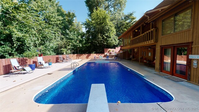 view of swimming pool featuring a patio, a diving board, and french doors