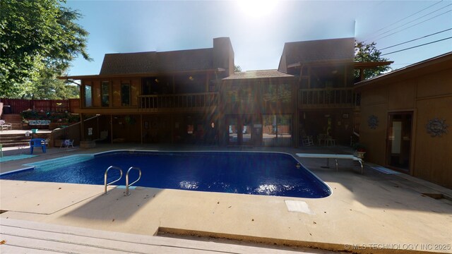 view of swimming pool featuring a patio and a diving board