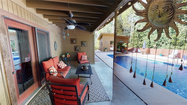 view of swimming pool featuring a shed, a patio area, and ceiling fan