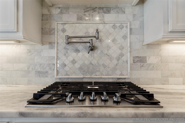 room details featuring light stone counters, white cabinets, and stainless steel gas stovetop