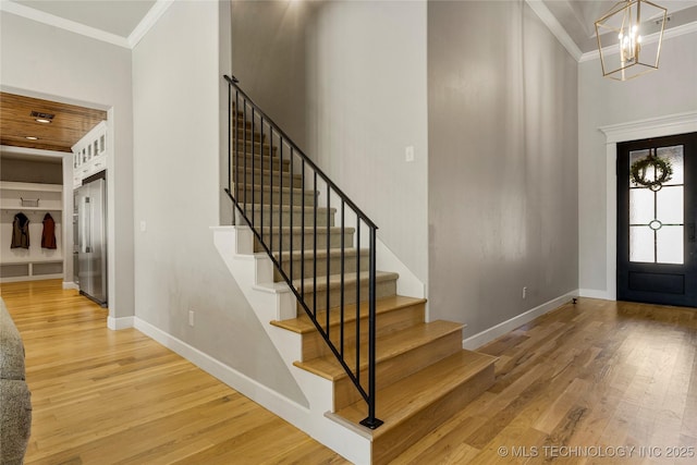 foyer entrance featuring hardwood / wood-style floors, crown molding, and a notable chandelier