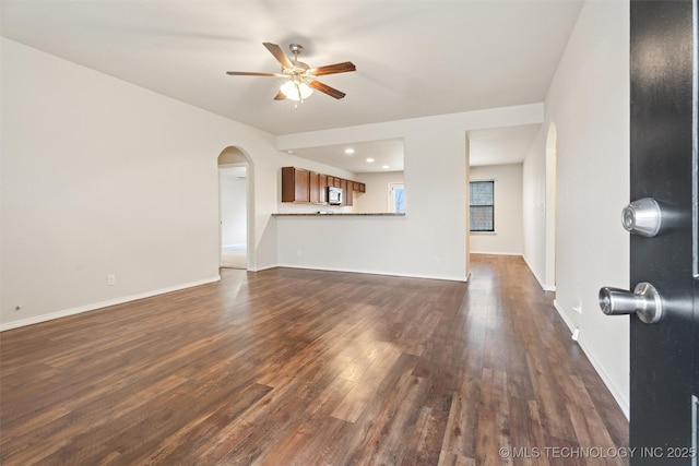 unfurnished living room with dark hardwood / wood-style floors and ceiling fan