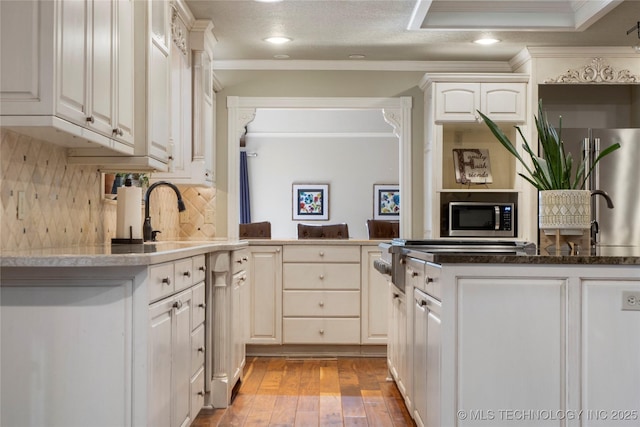 kitchen with crown molding, light hardwood / wood-style floors, tasteful backsplash, white cabinets, and stainless steel appliances