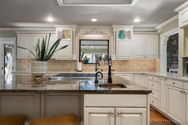 kitchen featuring crown molding, a textured ceiling, decorative backsplash, dark stone countertops, and a breakfast bar