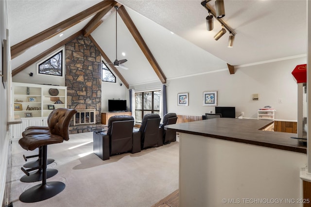 living room featuring a textured ceiling, light carpet, a fireplace, lofted ceiling with beams, and ceiling fan