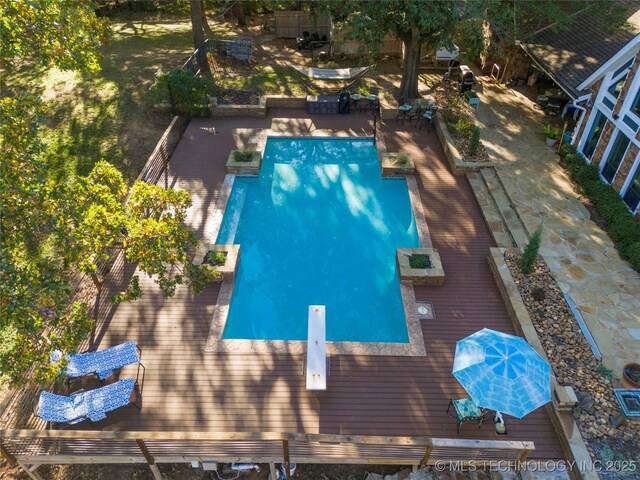 view of pool with a diving board and a deck