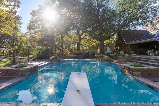 view of swimming pool with a diving board