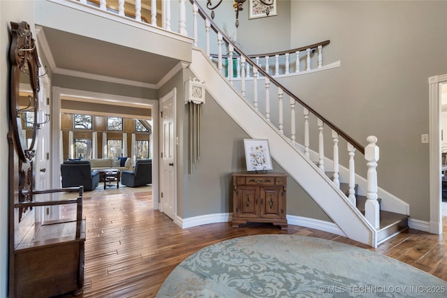 foyer with hardwood / wood-style floors, crown molding, and a towering ceiling